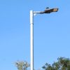 15W neutral white 4000K LED street light with IP66 rating and DALI compatibility, installed on a pole in a residential neighbourhood on a sunny day.