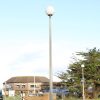 White opal sphere 30W street light on a 76mm post in an urban marina with a building and trees.